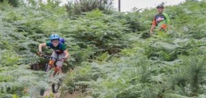 Happy child on a mountain bike, smiling as they cycle through nature, highlighting the fun and outdoor adventure of the sport