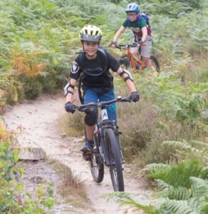 Happy child on a mountain bike, smiling as they cycle through nature, highlighting the fun and outdoor adventure of the sport
