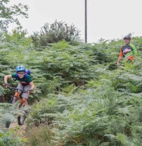 Happy child on a mountain bike, smiling as they cycle through nature, highlighting the fun and outdoor adventure of the sport