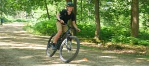 Happy child on a mountain bike, smiling as they cycle through nature, highlighting the fun and outdoor adventure of the sport