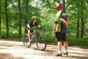 Happy child on a mountain bike, smiling as they cycle through nature, highlighting the fun and outdoor adventure of the sport