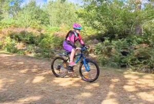 Happy child on a mountain bike, smiling as they cycle through nature, highlighting the fun and outdoor adventure of the sport