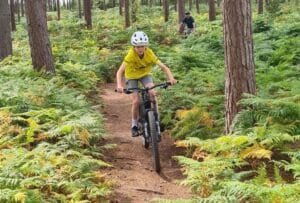 Happy child on a mountain bike, smiling as they cycle through nature, highlighting the fun and outdoor adventure of the sport