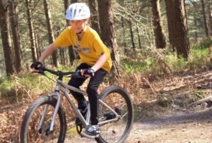 Happy child on a mountain bike, smiling as they cycle through nature, highlighting the fun and outdoor adventure of the sport