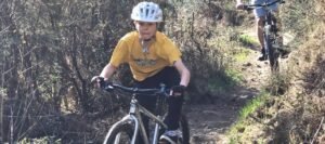 Happy child on a mountain bike, smiling as they cycle through nature, highlighting the fun and outdoor adventure of the sport