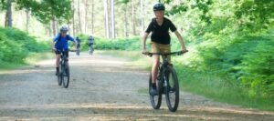 Happy child on a mountain bike, smiling as they cycle through nature, highlighting the fun and outdoor adventure of the sport