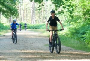 Happy child on a mountain bike, smiling as they cycle through nature, highlighting the fun and outdoor adventure of the sport