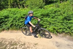 Happy child on a mountain bike, smiling as they cycle through nature, highlighting the fun and outdoor adventure of the sport